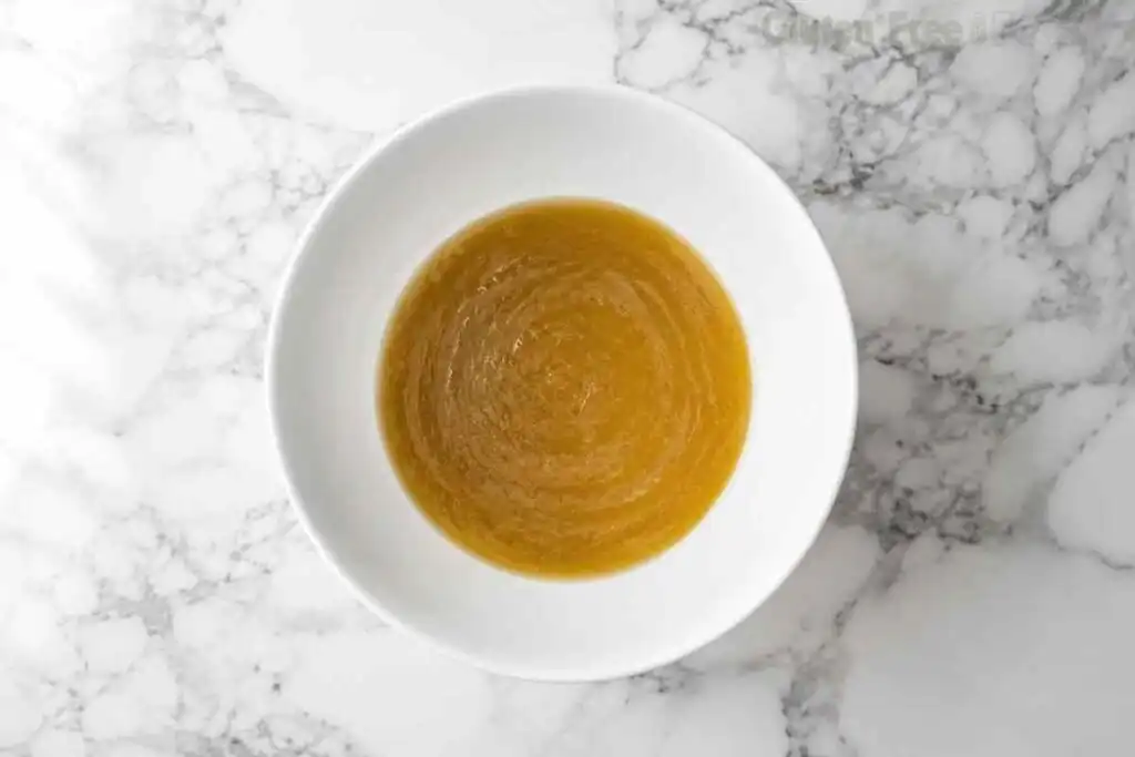 Melted butter, sugars, eggs, and vanilla whisked together in a white mixing bowl