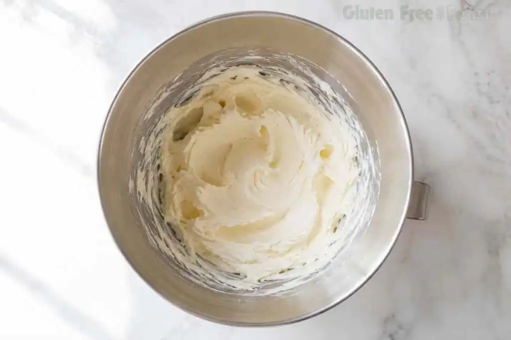 Butter and cream cheese beaten together in a stainless steel mixing bowl.