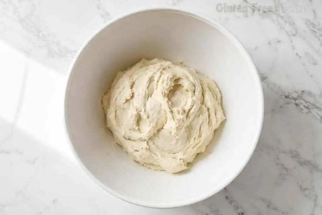 Sticky freshly mixed gluten free pizza dough in a mixing bowl