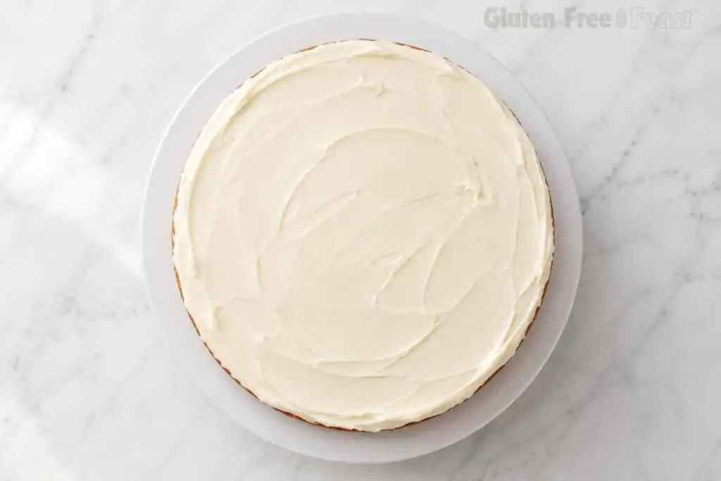Round gluten-free carrot cake layer covered with smooth cream cheese frosting.