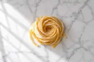 Homemade gluten-free fettuccine pasta nest on white marble