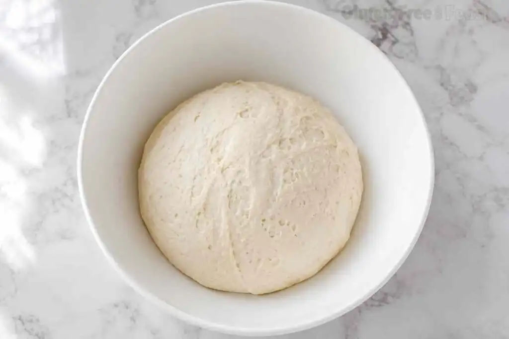 Proofed gluten free pizza dough after rising in a bowl
