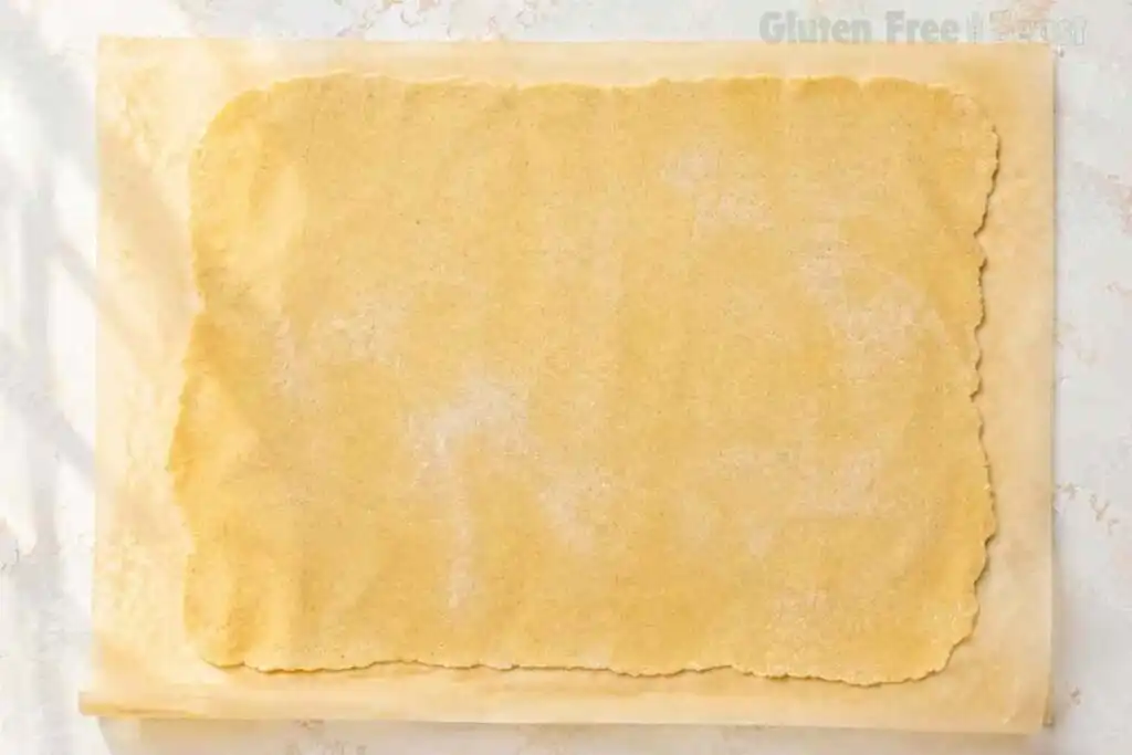 Thin sheet of gluten-free pasta dough rolled on parchment paper