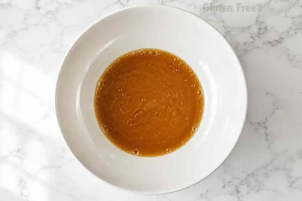 Deep amber brown butter poured into a large white bowl on marble