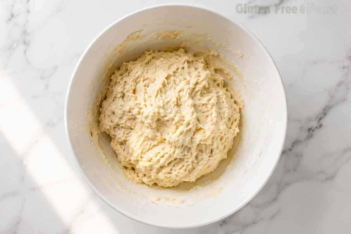 Shaggy gluten free biscuit dough just mixed in a white bowl after adding buttermilk soft and slightly sticky texture