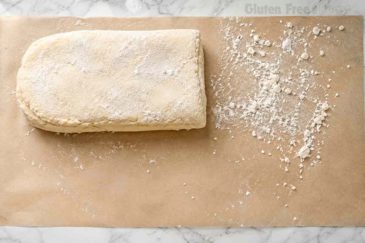 Gluten free biscuit dough folded a second time on parchment paper building light and flaky layers