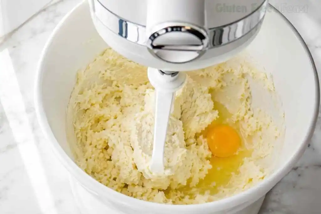 Egg added to creamed butter and sugar in a stand mixer for gluten free Christmas cookie dough
