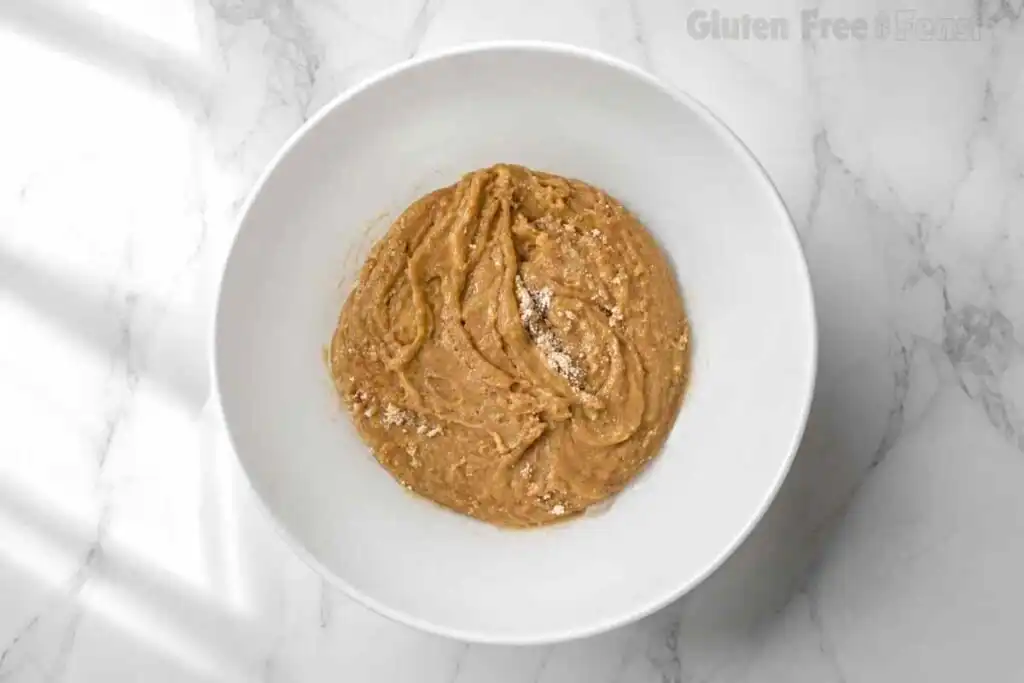 Brown butter, brown sugar, and egg whisked into a smooth, glossy wet mixture in a white bowl