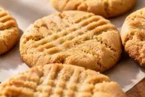 Soft and chewy gluten free peanut butter cookies with classic fork cross-hatch marks and lightly crisp golden edges on parchment paper