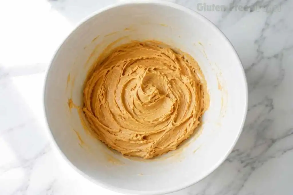 Smooth creamed mixture of peanut butter, softened butter, granulated sugar and brown sugar in a large white ceramic bowl on marble after beating with a hand mixer for 2 minutes