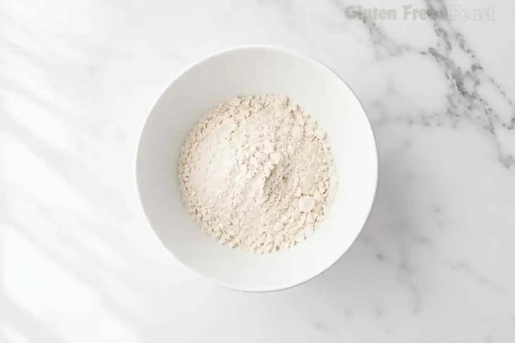 Gluten free flour and almond flour whisked together in a white bowl on a marble surface