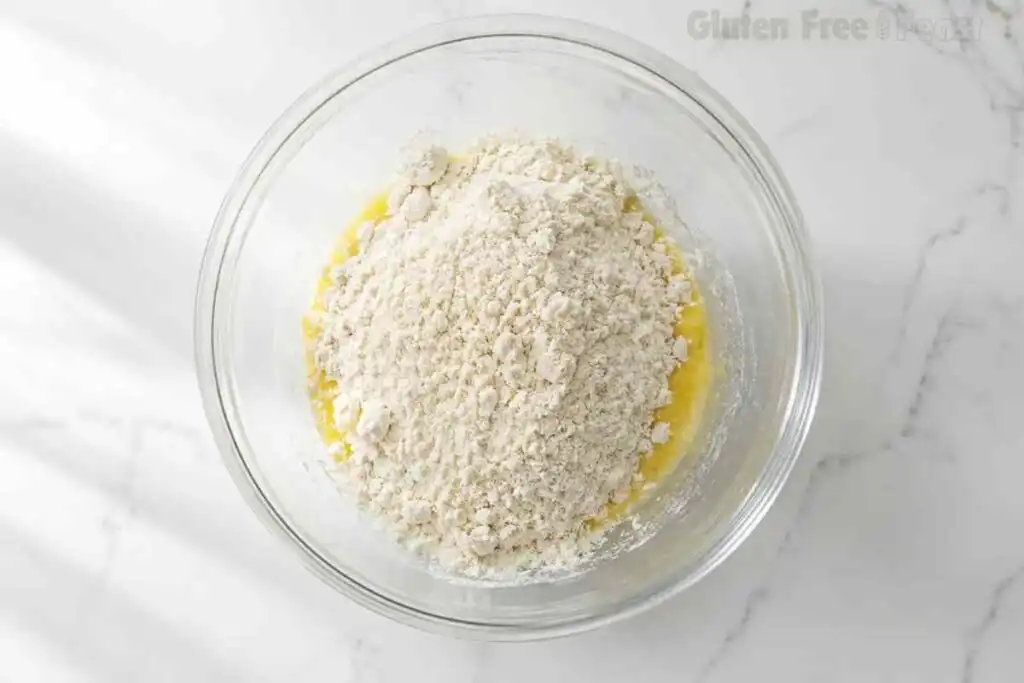 Gluten-free baking mix added to whisked eggs in a glass bowl