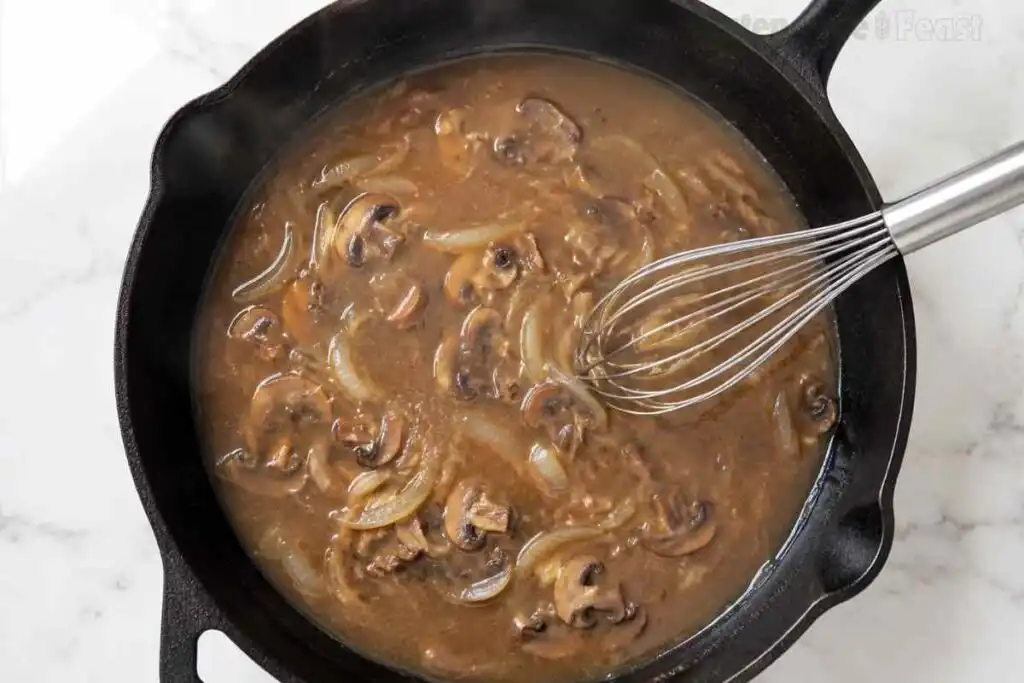Whisking creamy gluten-free mushroom stroganoff sauce in a cast iron skillet.