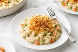 Creamy gluten free crustless chicken pot pie topped with toasted gluten-free panko breadcrumbs on a white plate