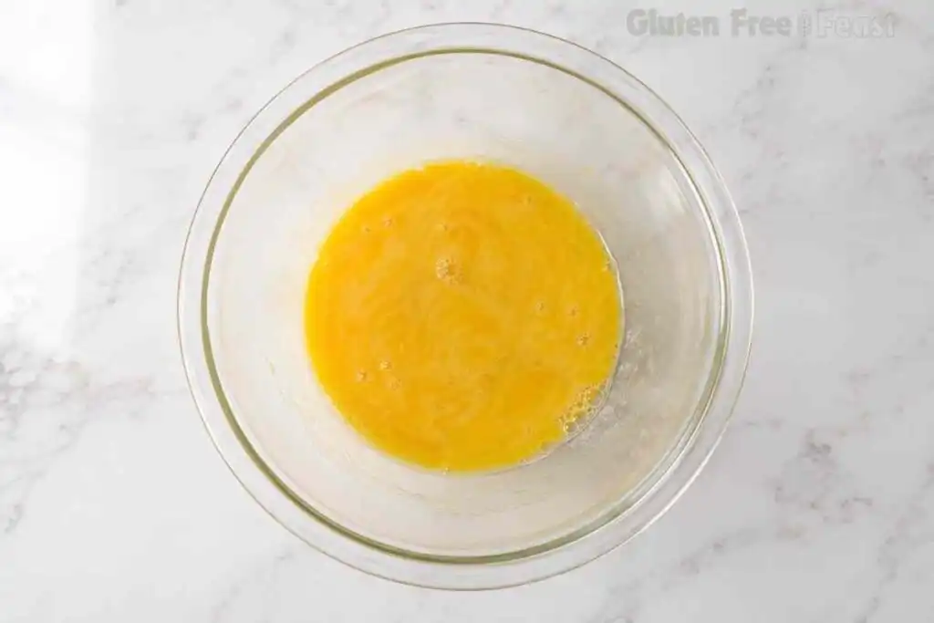 Partially whisked eggs in a clear glass mixing bowl